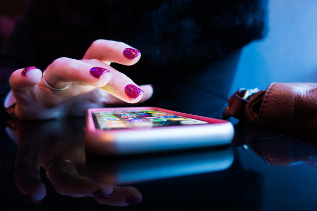 Hand touching phone screen on table