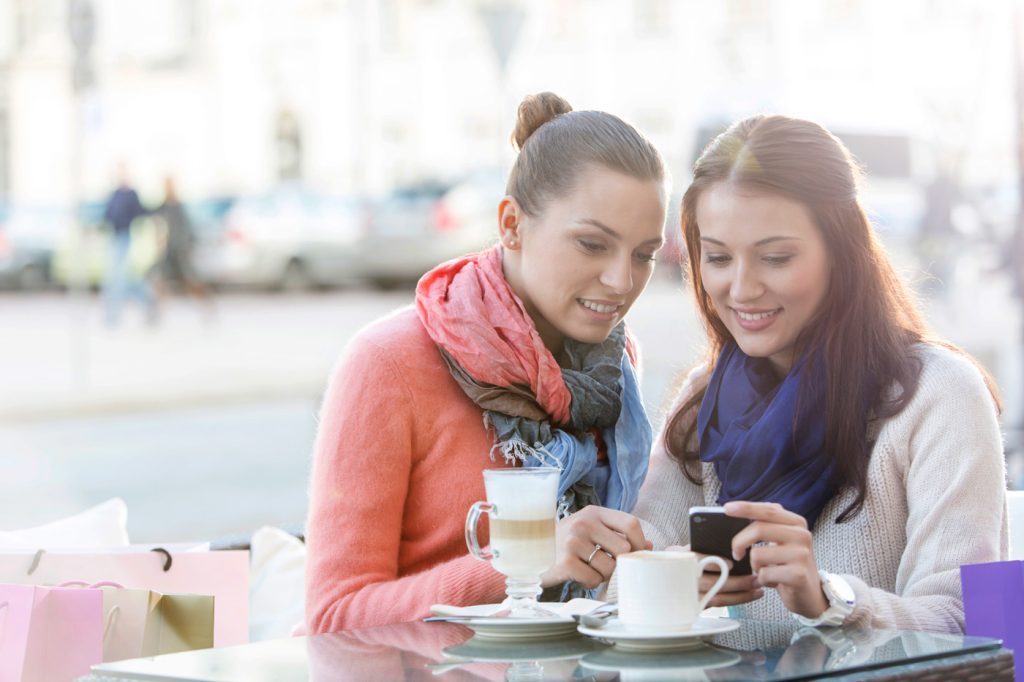 Women looking at phone at cafe