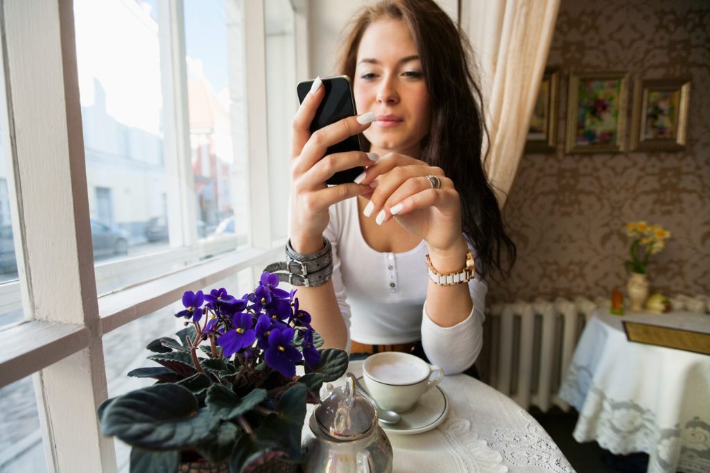 Women reading phone having coffee